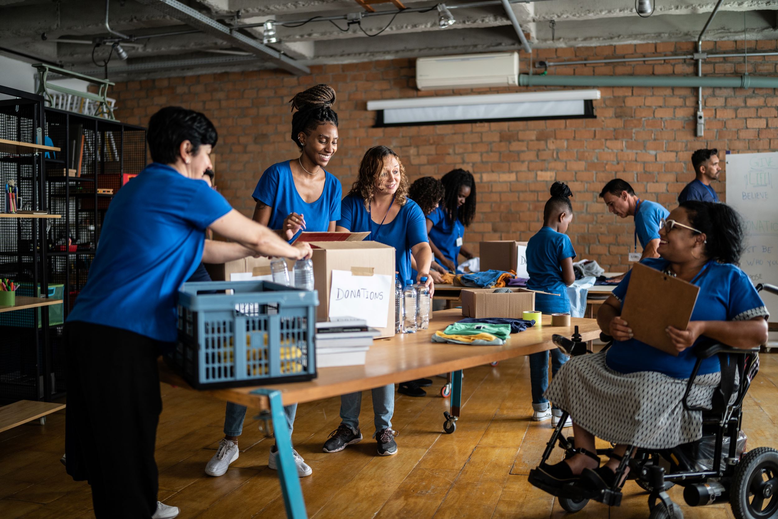 CHWs arrange donations in a community center. The CHWs have a variety of skin tones and one uses a wheelchair. 